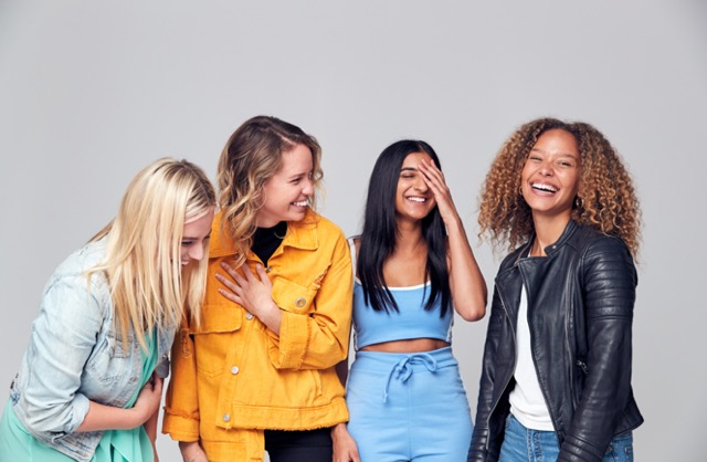 Group Studio Portrait Of Multi-Cultural Female Friends Smiling Into Camera Together